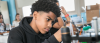 Young student in classroom with science equipment on foreground